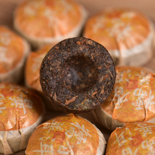 Tea cakes wrapped in orange and white paper with a single open tea cake on top.